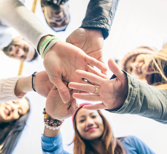 Group with hands together ready to take on a challenge and develop Psychological Resilience.